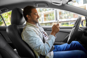 Homem dentro do carro utilizando o celular para acessar serviços digitais do CONTRAN, como CNH Digital e CRLV-e.