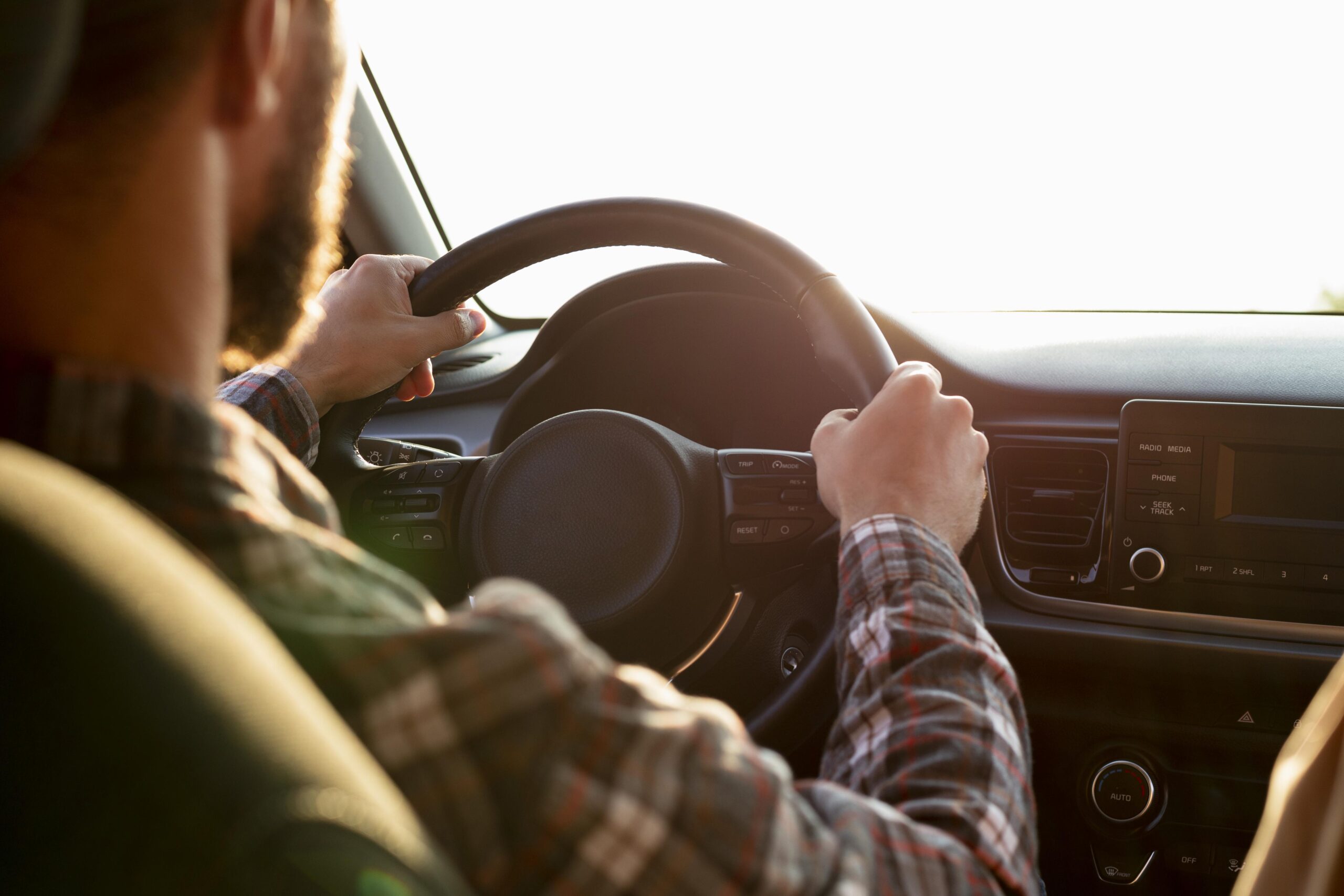 Homem com as mãos no volante representando a atenção às regras da resolução do CONTRAN para motoristas.
